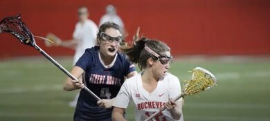 Two girls are playing lacrosse