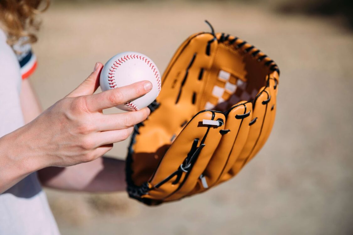 The woman is holding a baseball and a glove