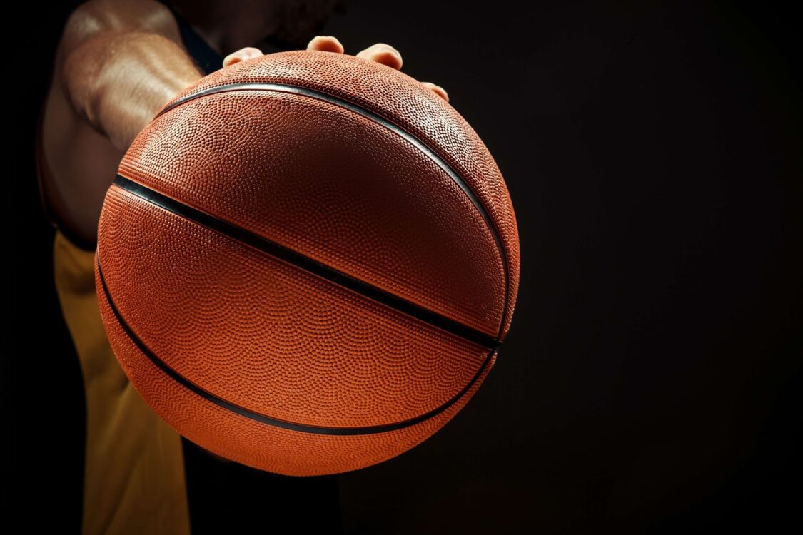 Man holding a basketball on black background