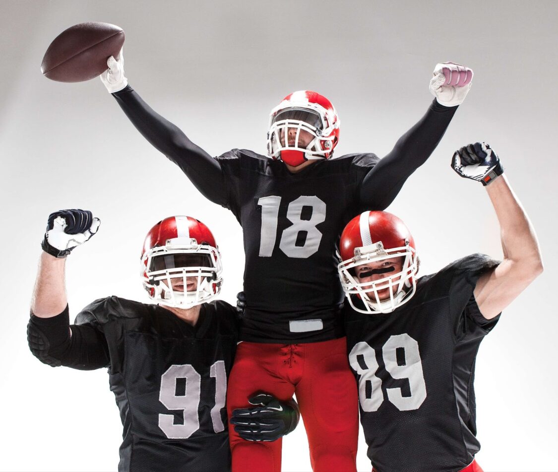 Three American football players celebrate a victory