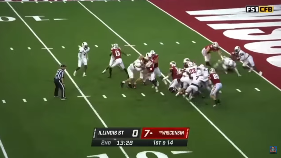 two walk-on football teams on the field during gameplay and a referee observing them