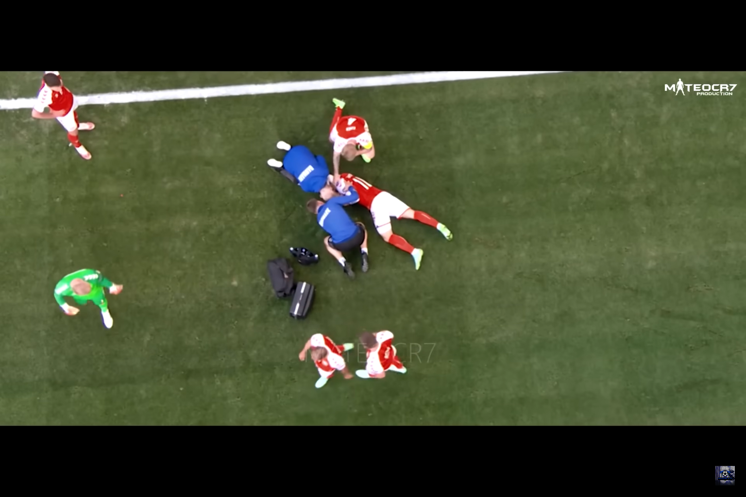 An unconscious football player lies on the field, doctors help him