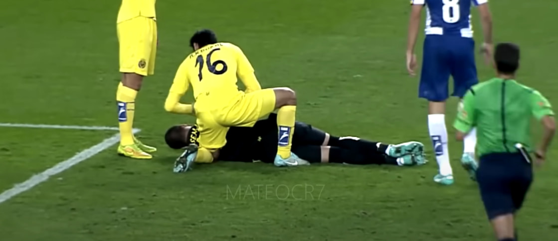 A football player helps another player who is lying on the field