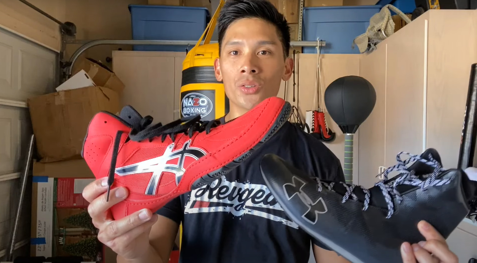A man holds two pairs of wrestling shoes in his hands